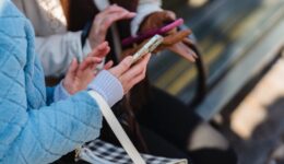 women touching screens of smartphones in park